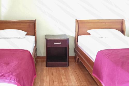 two twin beds in a room with a table between them at Hotel Bumi Bermi Permai near Bermi Eco Park Mitra RedDoorz in Probolinggo
