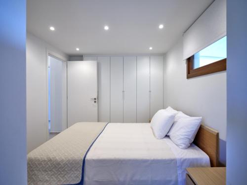 a bedroom with a bed with white sheets and a window at Forecastle in Keratea