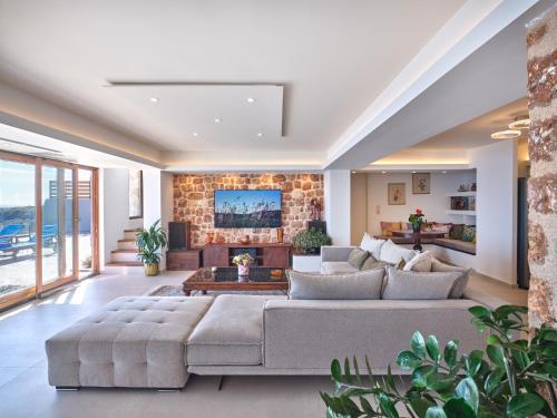 a living room with a large couch and a stone wall at Forecastle in Keratea