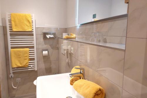ein Bad mit einem Waschbecken und einem gelben Handtuch in der Unterkunft Pension Zur alten Mühle in Sölden