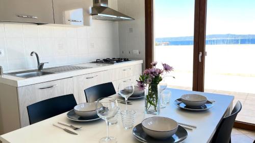 a kitchen with a table with plates and wine glasses at Attici con Terrazzo vista Mare in Calasetta