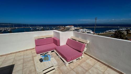 two chairs on a balcony with a view of a harbor at Attici con Terrazzo vista Mare in Calasetta