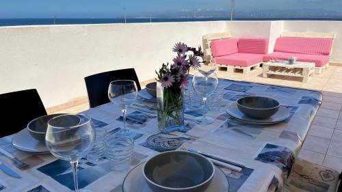 a table with wine glasses and a vase of flowers at Attici con Terrazzo vista Mare in Calasetta