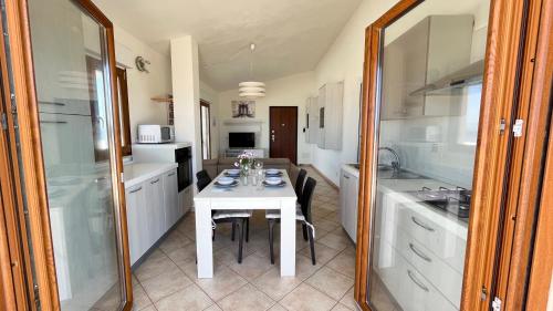 a kitchen with a white table and a white counter top at Attici con Terrazzo vista Mare in Calasetta