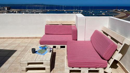 two pink chairs and a table on a roof at Attici con Terrazzo vista Mare in Calasetta