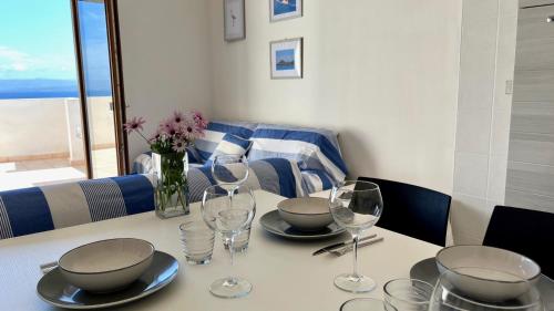 a table with bowls and wine glasses on it at Attici con Terrazzo vista Mare in Calasetta