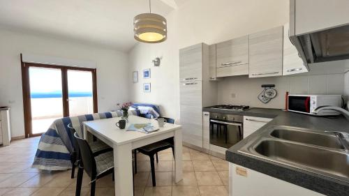 a kitchen with a table and a sink and a counter at Attici con Terrazzo vista Mare in Calasetta