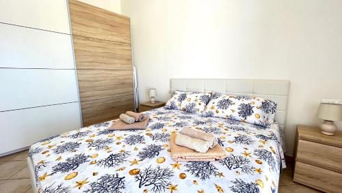 a bedroom with a bed with a blue and white comforter at Attici con Terrazzo vista Mare in Calasetta