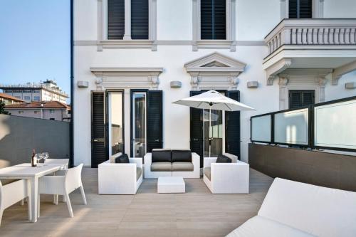 a balcony with white chairs and tables and an umbrella at LHP Hotel Montecatini Palace & SPA in Montecatini Terme