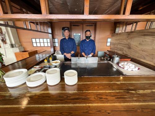 two men are standing in a kitchen with plates at Sea Passion Hotel in Koror