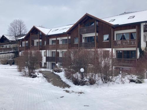 a large wooden building with snow on the ground at Bergsonnenblick Bad Hindelang in Bad Hindelang