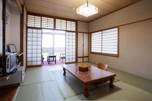 a living room with a table and a tv at Hotel Yakushima Sanso in Yakushima