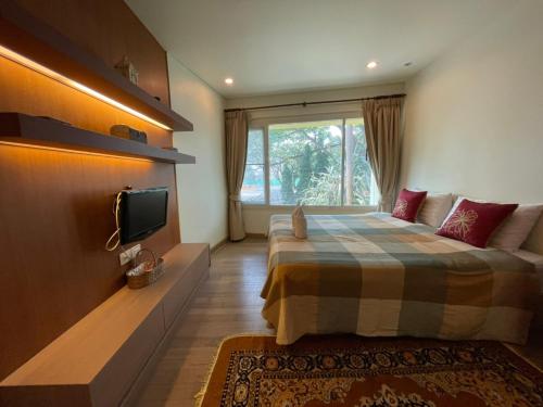 Un dormitorio con una cama y un televisor y una ventana. en My Mykonos มายมิโคนอส, en Hua Hin