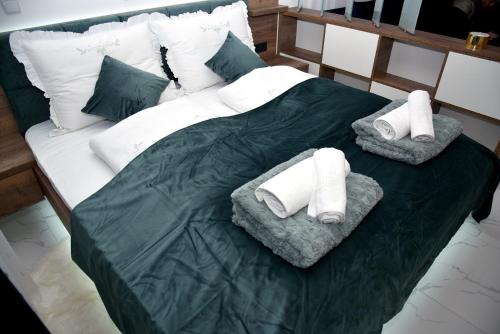 uma cama com duas toalhas e almofadas em La Luna Premium Deluxe Apartment with Free Jacuzzi, Bikes & Covered Parking em Našice