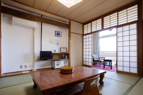 pokój z drewnianym stołem w pokoju z oknami w obiekcie Hotel Yakushima Sanso w mieście Yakushima