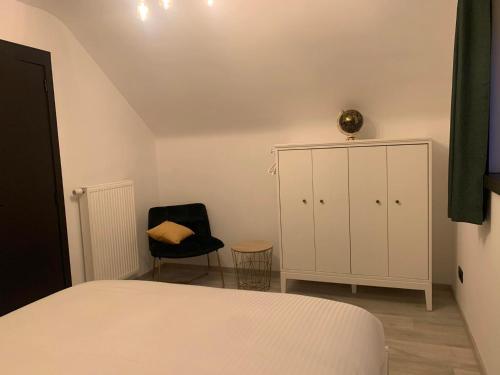 a bedroom with a bed and a cabinet and a chair at Gites douillets à l’orée des bois. in Houyet