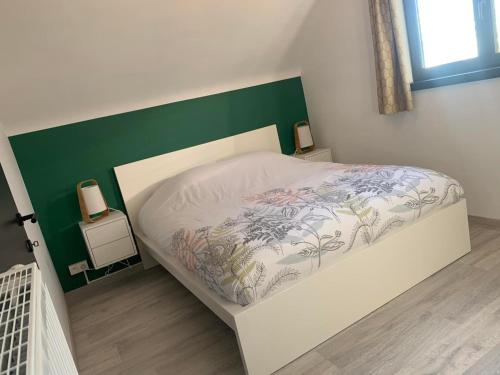 a small bedroom with a bed with a green headboard at Gites douillets à l’orée des bois. in Houyet
