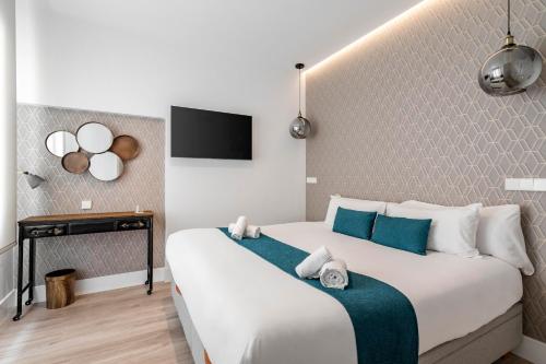 Un dormitorio con una gran cama blanca con toques azules en Marco Polo Residence Hostal Boutique, en Madrid