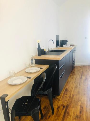 a kitchen with a sink and a wooden table with chairs at studio moderne et confortable Le nid in Cholet