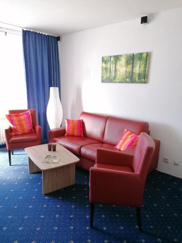 sala de estar con sofá rojo y 2 sillas en Kranichsee-Apartment, en Goslar