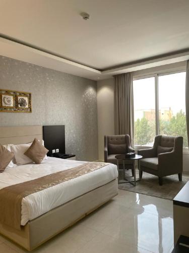 a bedroom with a bed and two chairs and a television at شقق قولد ان للشقق المخدومة in Riyadh