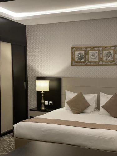 a bedroom with a large bed with a lamp and pillows at شقق قولد ان للشقق المخدومة in Riyadh