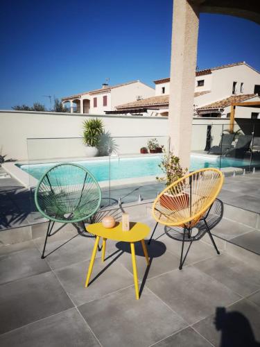 - 2 chaises et une table sur une terrasse avec piscine dans l'établissement Appartement au dessus de la maison du Saunier, à Salin-de-Giraud