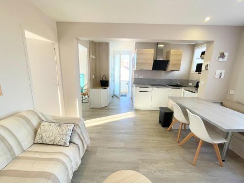 un salon et une cuisine avec un canapé et une table dans l'établissement Gîte Le Plessis Océan à 200m de la mer, parking privé et jardin clos, à Pornic