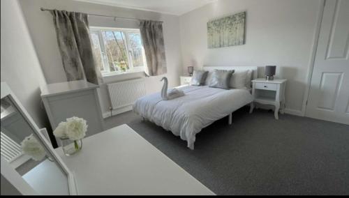 a white bedroom with a bed and a window at A beautiful house in a scenic town location. in Louth
