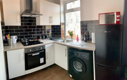 eine Küche mit einem schwarzen Kühlschrank und einem Geschirrspüler in der Unterkunft Apartment in City centre, 4 guests, CAR PARK in Doncaster