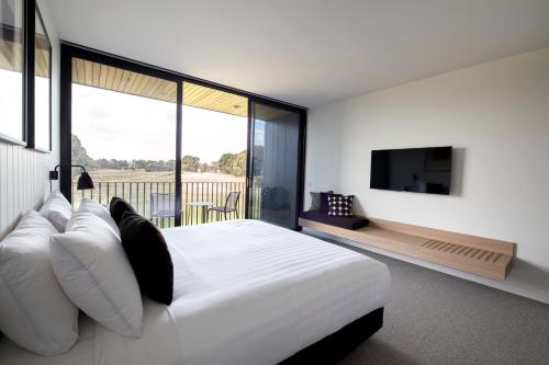 a bedroom with a large white bed and a television at Accommodation @ Curlewis in Curlewis