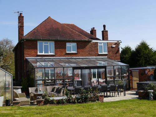a house with a conservatory with tables and chairs at South View Country House Sleeps 12 - Hot Tub - Views in Henley in Arden