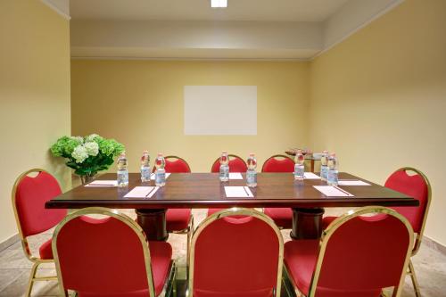 a conference room with a table and red chairs at Hotel Mythos in Milan