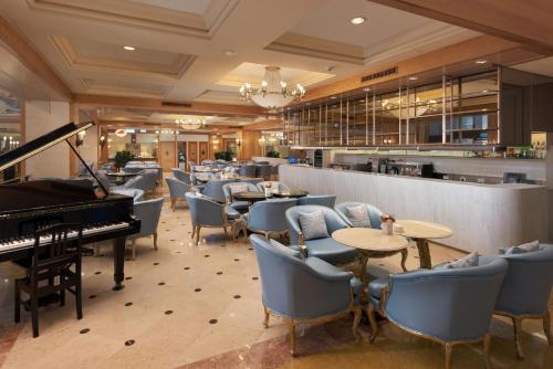 高雄的住宿－漢來大飯店，一间设有钢琴和桌椅的餐厅