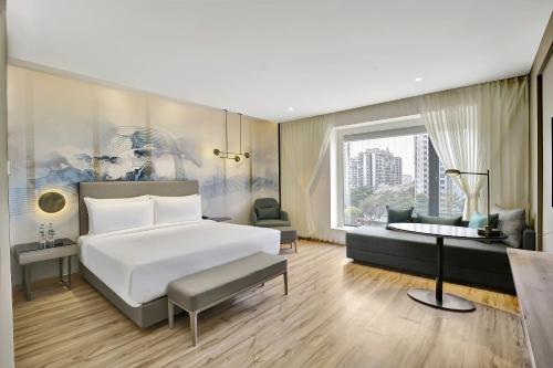 a bedroom with a bed and a living room at Park Inn by Radisson Surat in Surat