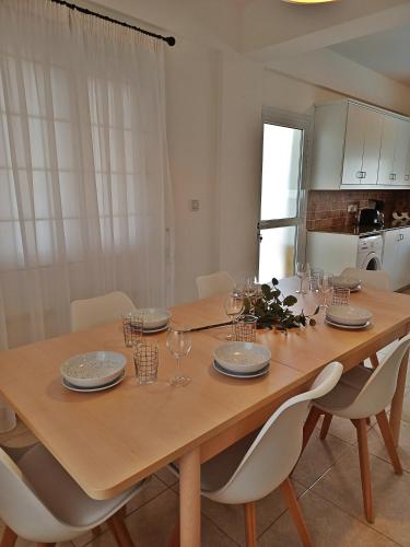 a dining room table with white chairs and a kitchen at Protaras sea view Villa with private pool in Protaras