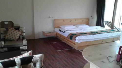 a bedroom with a bed and a chair and a table at Zizina Otis Resort in Guwahati