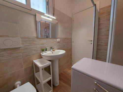 a bathroom with a sink and a toilet and a mirror at Serena 2-8 in Lido di Pomposa