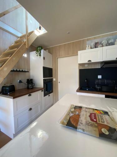 a kitchen with white cabinets and a staircase at Tiny et Jacuzzi Charente Maritime in Plassay