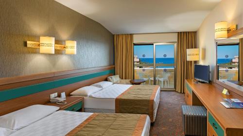 a hotel room with two beds and a television at Özkaymak Incekum Resort - Ultra All Inclusive in Avsallar