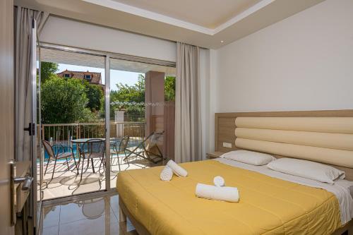 a bedroom with a yellow bed and a balcony at Caretta Beach Resort & WaterPark in Kalamaki