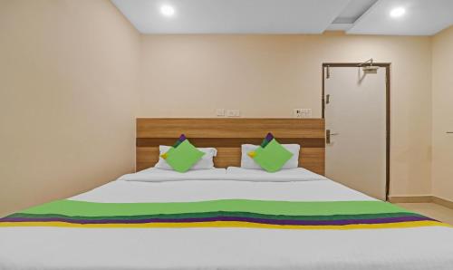 a bedroom with a large white bed with green pillows at Treebo Pride Inn Botanica in Hyderabad