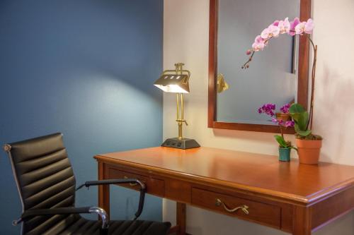 a desk with a lamp and a mirror and a chair at Federal City Inn & Suites in New Orleans