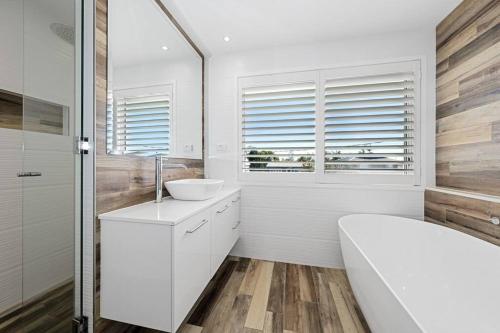 a bathroom with a white tub and a sink and a tubermott at Sea Spray- Private Pool, Beach, Table Tennis in The Entrance