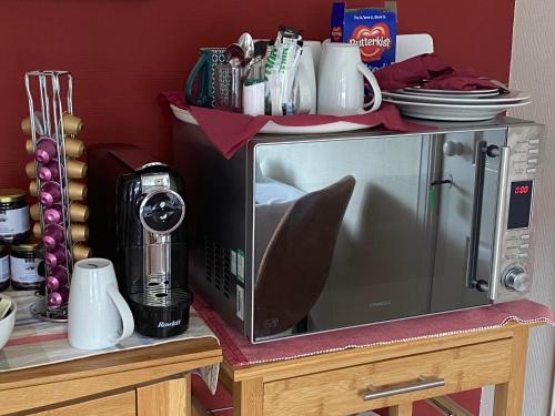 a microwave oven sitting on a table with dishes on it at Rowan House B&B Rooms & A Self Catering Apartment in Lochgoilhead