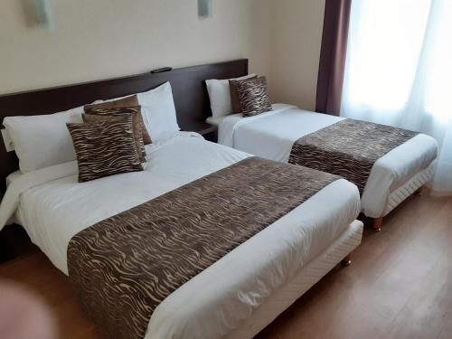 a hotel room with two beds with brown and white sheets at Le Chapeau Rouge in Alençon