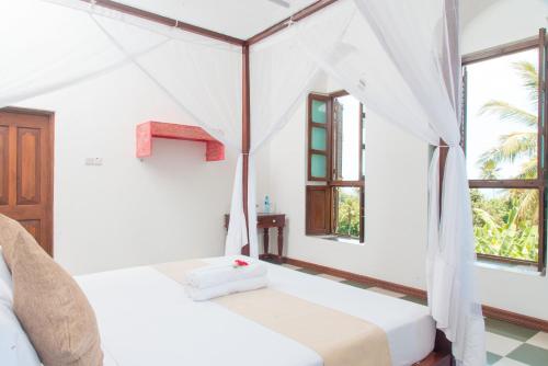 a bedroom with two beds in a room with windows at The Manor House by Sansi in Zanzibar City