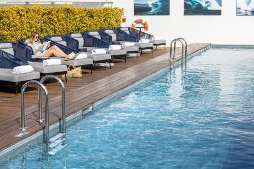 a woman sitting on chairs next to a swimming pool at Hotel Indigo Cagnes-sur-Mer, an IHG Hotel in Cagnes-sur-Mer