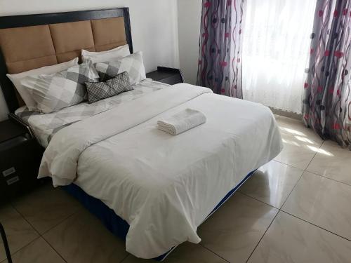 Una cama con un edredón blanco y dos toallas. en FRANCHISE BENONI GUEST HOUSE en Benoni