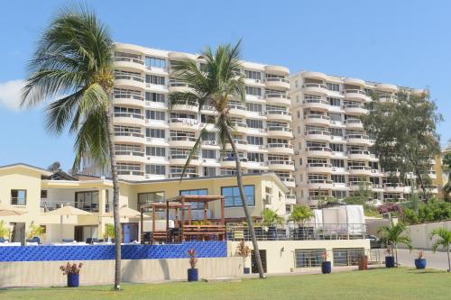 a large building with palm trees in front of it at Jumeirah Beachfront in Mombasa